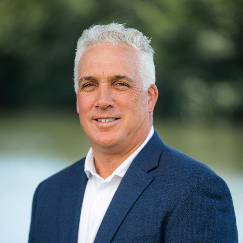 A confident middle-aged man in a blue blazer outdoors.